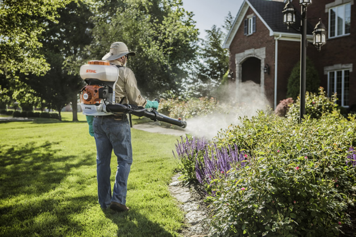 exterminator spraying lawn of residential area